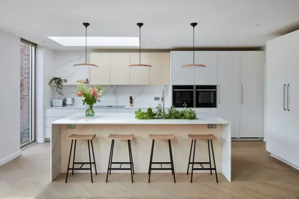 Cuisine moderne avec îlot central, tabourets en bois et une niche ouverte intégrée dans les placards.
